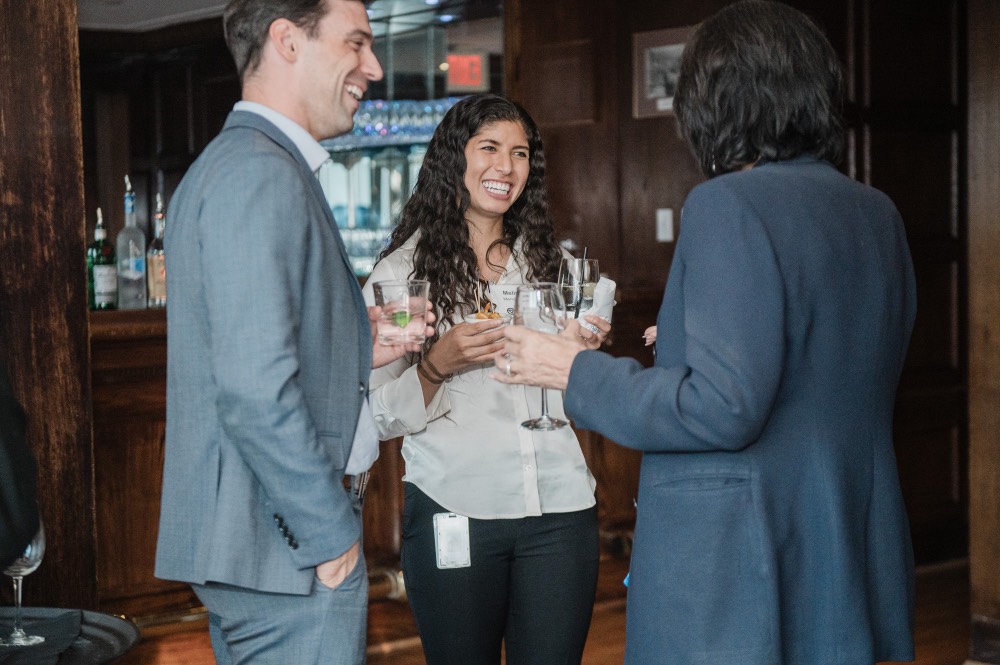2 GVSU Alumni smiling as they talk to President Mantella